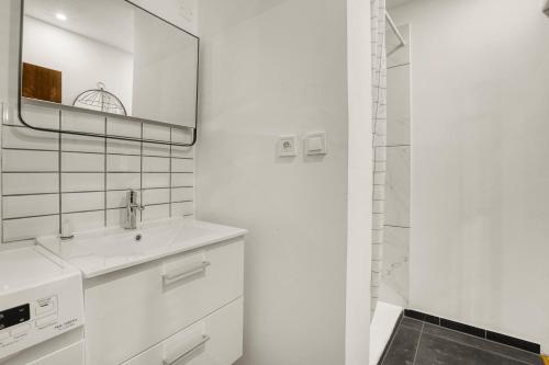 une salle de bain blanche avec un lavabo et un miroir dans l'établissement Appartement Cosy - Terrasse - Proche Métro, à Toulouse