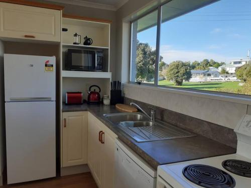 a kitchen with a sink and a white refrigerator at 3 bedroom holiday home in prime Kaikoura location! in Kaikoura