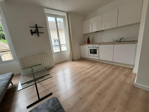 an empty living room with a couch and a kitchen at Ma Belle Conciergerie - Le Petit Coin de Milly in Milly-la-Forêt