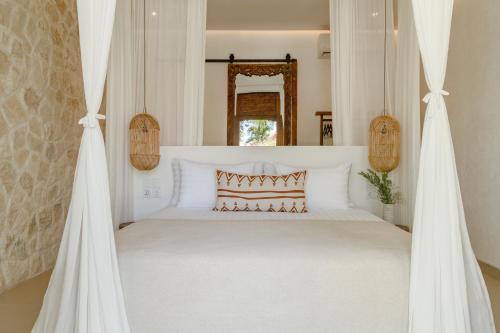 a bedroom with a white bed with a canopy at The Balangan Hotel in Jimbaran