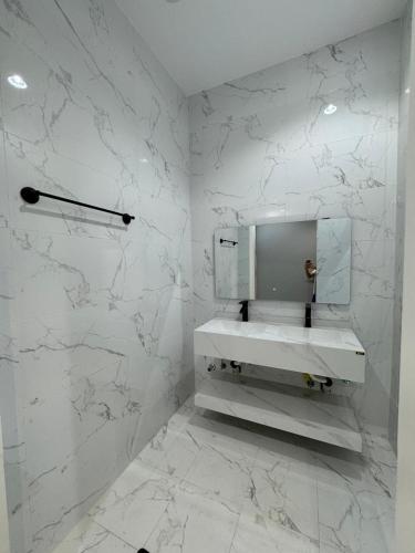 a white bathroom with a sink and marble walls at توتn in Hail