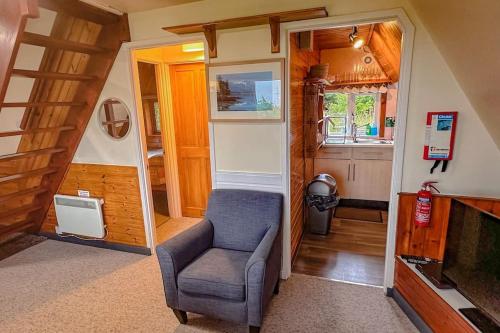 a living room with a chair and a tv at 1 Bedroom Cabin with Mountain & Loch Views - Quiet Location between Glencoe & Ben Nevis in Corran