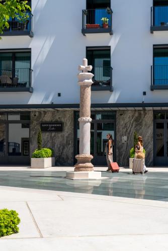 a column in front of a building with people sitting on benches at Savoy Insular VI by An Island Apart in Funchal