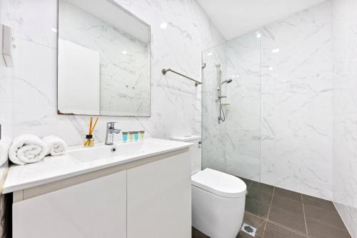 a white bathroom with a toilet and a sink at Burwood 1Br studio nearTrain StationShopping in Sydney