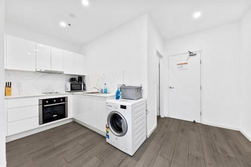 a white kitchen with a washing machine in it at Burwood 1Br studio nearTrain StationShopping in Sydney