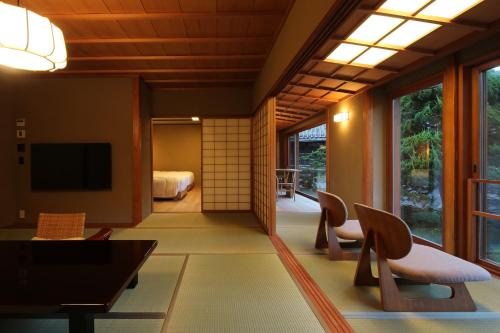 a room with a living room with a television and chairs at Nishimuraya Honkan in Toyooka