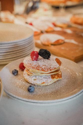 a stack of pancakes with berries on a plate at Anett hotel in Vipiteno