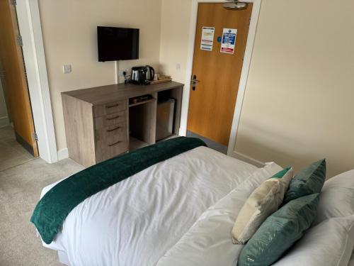 a bedroom with a white bed with a green blanket at Class Stays in Shrewsbury