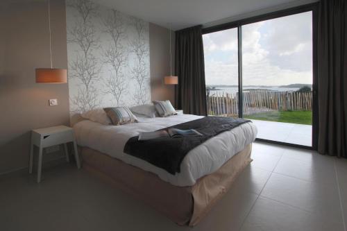 une chambre avec un grand lit et une grande fenêtre dans l'établissement Villa des Agapanthes, à Pleumeur-Bodou