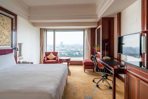 a hotel room with a bed and a desk and a window at Shangri-La Guangzhou-Walking to Canton Fair Complex in Guangzhou