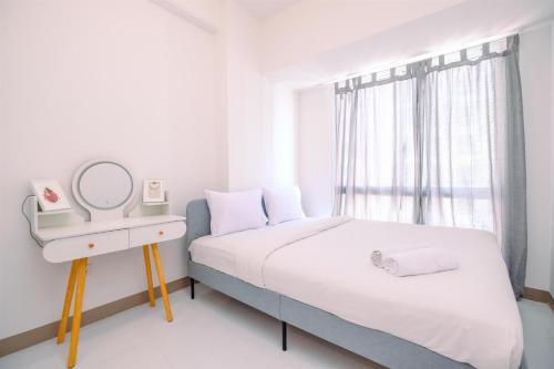 a white bedroom with a bed and a mirror at Comfort and Nice 2BR at Tokyo Riverside PIK 2 Apartment By Travelio in Rawalembang