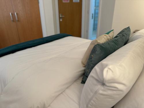 a white bed with green pillows on it at Class Stays in Shrewsbury