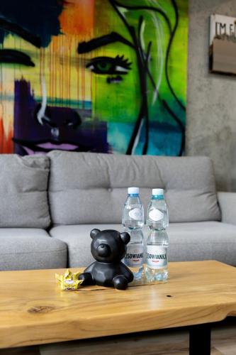 a teddy bear sitting on a coffee table with two water bottles at Art Apart in Płock
