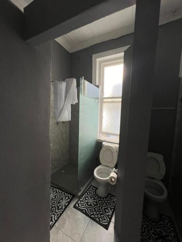 a bathroom with a toilet and a shower and a window at CapePod Sea Point in Cape Town
