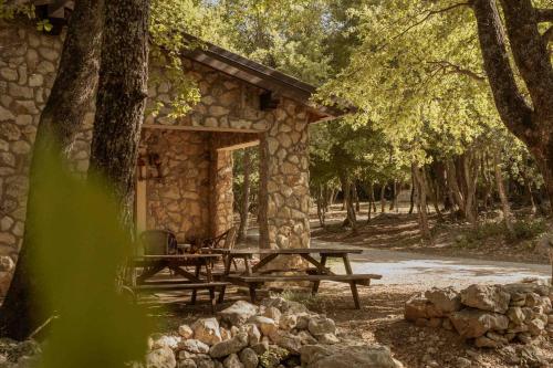 a stone cabin with a picnic table in the woods at Il Rifugio dei Briganti in Caramanico Terme