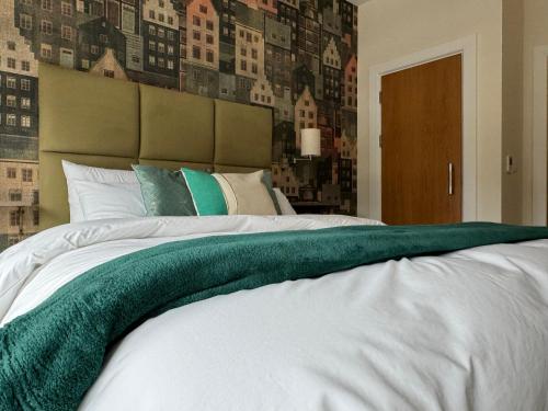 a large white bed with a green blanket on it at Class Stays in Shrewsbury