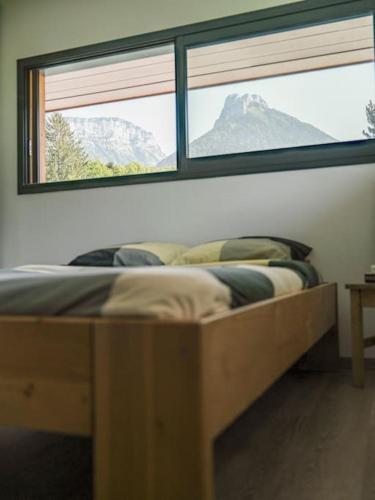 un lit dans une chambre avec une grande fenêtre dans l'établissement Venez Chez Vous Villa Nature, à Alex
