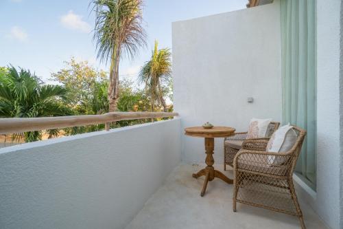 a balcony with chairs and a table and palm trees at The Balangan Hotel in Jimbaran