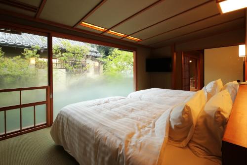 a bedroom with a large bed and a large window at Nishimuraya Honkan in Toyooka