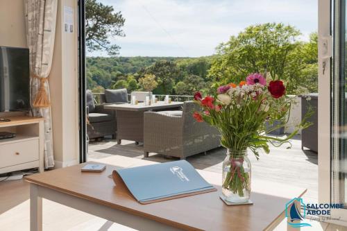ein Tisch mit einer Vase mit Blumen darauf in der Unterkunft Elevated Coastal Escape - Breathtaking Views in Salcombe