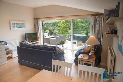 ein Wohnzimmer mit einer blauen Couch und einem großen Fenster in der Unterkunft Elevated Coastal Escape - Breathtaking Views in Salcombe