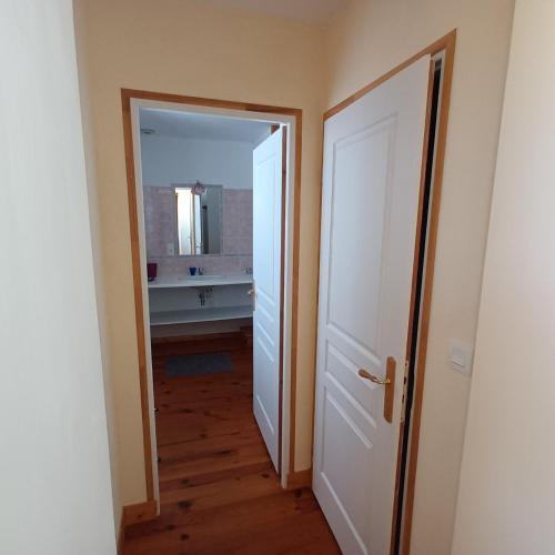 une porte ouverte menant à une salle de bain avec un miroir dans l'établissement Chambre des bords de Siame, à Gratot