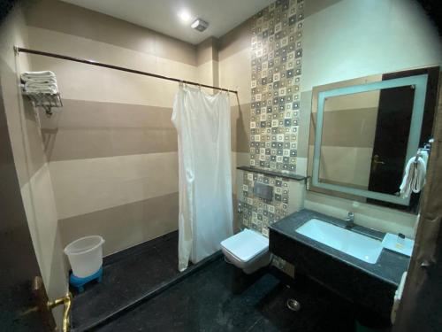a bathroom with a sink and a toilet and a mirror at HotelMaple Ridge in Tājganj
