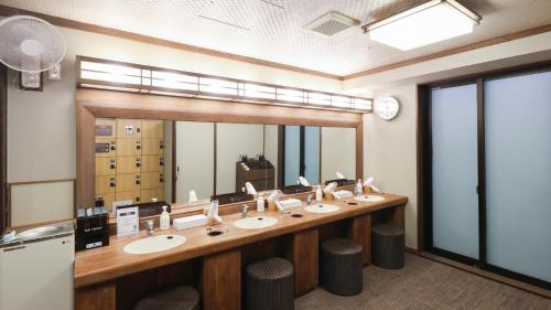 a bathroom with a row of sinks and a large mirror at Dormy Inn Sendai Annex in Sendai