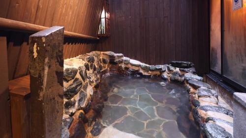 a jacuzzi in a room with a stone wall at Dormy Inn Sendai Annex in Sendai