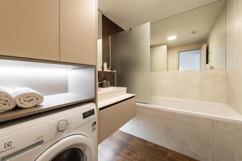 a bathroom with a washing machine and a bath tub at Nikas Eurovea Apartments - free parking in Bratislava