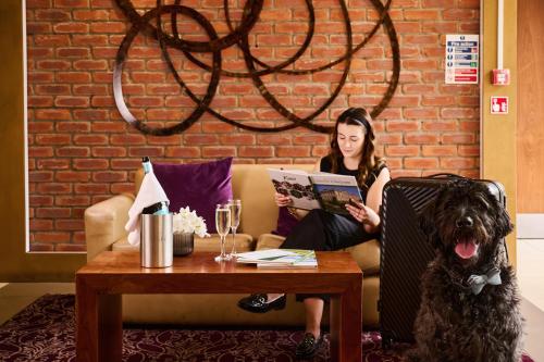a woman sitting on a couch reading a book next to a dog at The Rutland Hotel in Sheffield