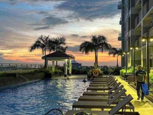 a pool at a hotel with benches and palm trees at Luxurious Bayview 2BR Near MOA PICC CCP Free WiFi in Pasay in Manila