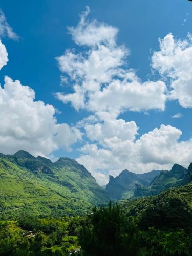 a green valley with mountains under a cloudy sky at Tày Cốc Pảng Homestay in Làng Cac
