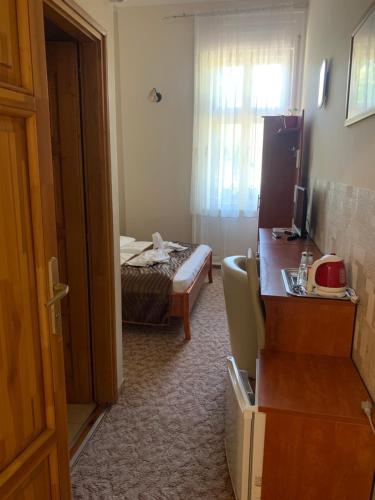 a room with a bedroom with a bed and a desk at Szent István Wellness Panzió in Makó