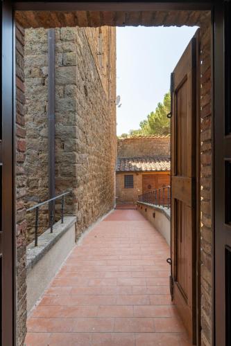 an alley with a brick wall and a door at Palazzo Massaini - Le Scuderie in Pienza