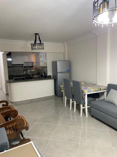 a living room with a table and chairs and a kitchen at الساحل الشمالي شاليه مكيف قريه مارسليا بيتش 4 in Sīdī ‘Abd ar Raḩmān