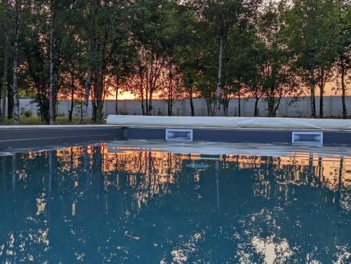 ein Teich neben einer Straße mit Bäumen in der Unterkunft L' Évasion en plein air in Fontenay-sur-Loing