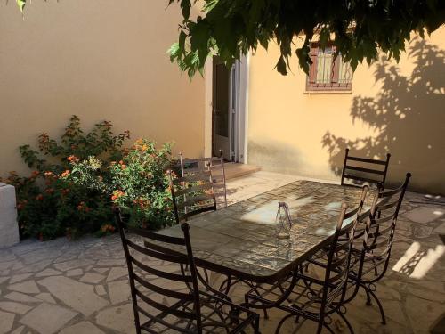 a dining table with chairs and flowers on a patio at L'Ostal de Terralha avec piscine au centre du village in Montfrin
