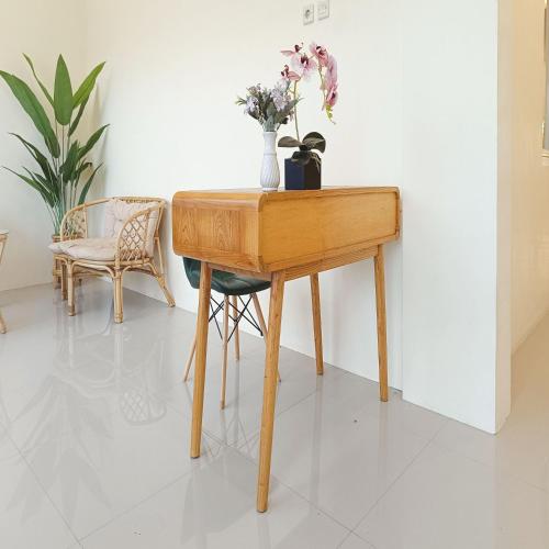 a wooden table with a vase of flowers on it at Nawasena Homey Syariah near Bandara Adisucipto 4 Mitra RedDoorz in Potrojayan