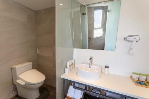 a bathroom with a toilet and a sink and a mirror at Green Hotel - Chiayi in Chiayi City