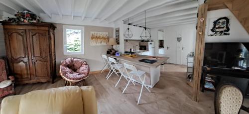 une cuisine et un salon avec une table et des chaises dans l'établissement Le CHALET FLEURI, à Colleville-Montgomery