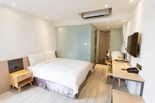 a hotel room with a bed and a desk at Green Hotel - Chiayi in Chiayi City