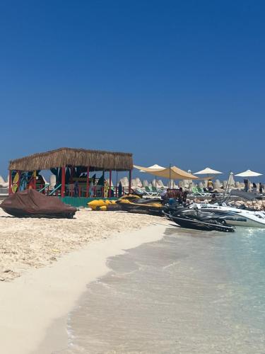 a beach with a pavilion and boats on the sand at الساحل الشمالي شاليه مكيف قريه مارسليا بيتش 4 in Sīdī ‘Abd ar Raḩmān