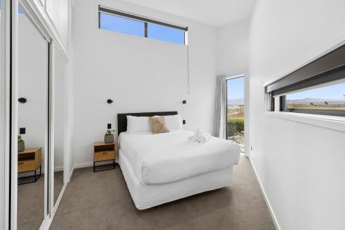 a white bedroom with a bed and a window at Boutique One Bedroom Haven in Wanaka