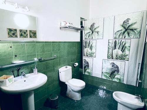 a bathroom with a toilet and a sink with green tiles at Apartamentos Turísticos Architettura Úbeda in Úbeda