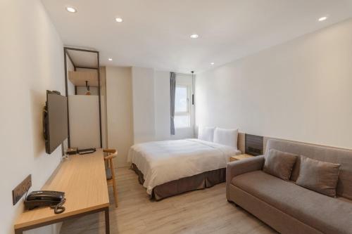 a hotel room with a bed and a couch at Green Hotel - Chiayi in Chiayi City