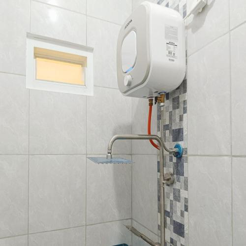 a shower in a tiled bathroom with a toilet at Nawasena Homey Syariah near Bandara Adisucipto 4 Mitra RedDoorz in Potrojayan