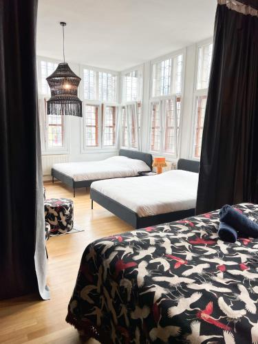 a bedroom with two beds and a room with windows at Le FauBourg Suites in Antwerp