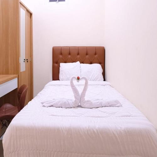 two swans made out of towels on a bed at Nawasena Homey Syariah near Bandara Adisucipto 4 Mitra RedDoorz in Potrojayan