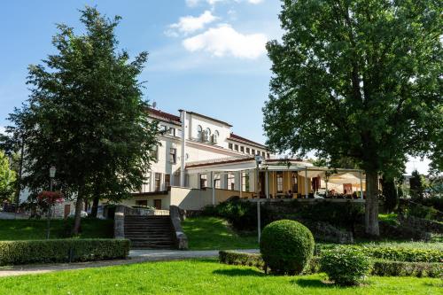 a large white house with trees and a lawn at Hotel Cēsis in Cēsis